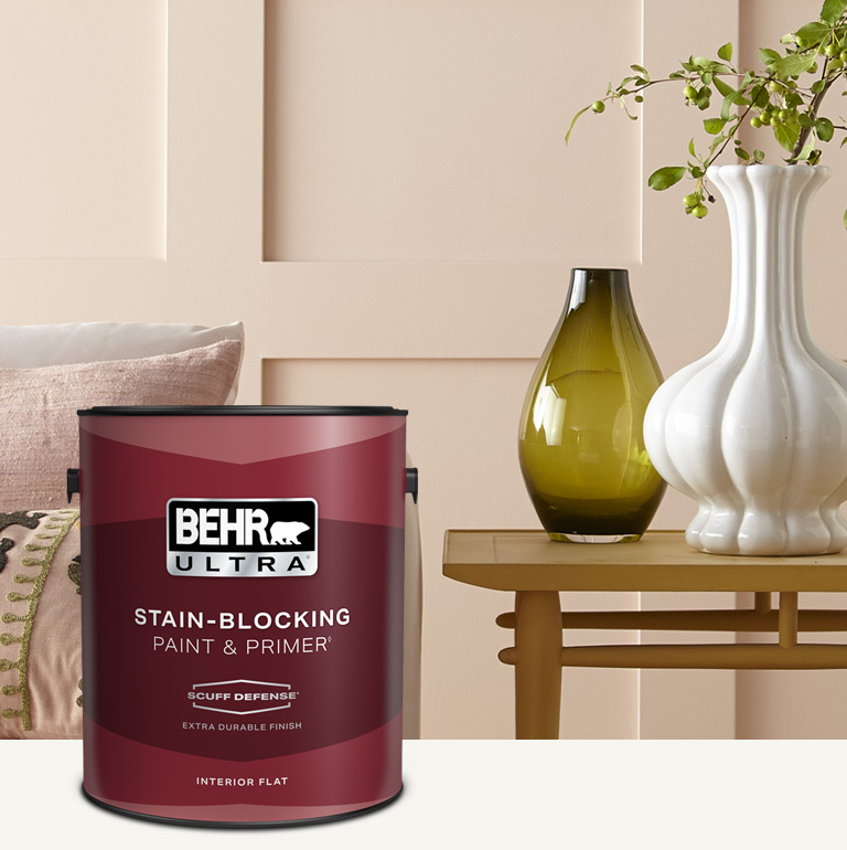 Living room with a pale peach colored wall and a can of Behr Ultra Scuff Defense Interior Paint in the foreground mobile image.